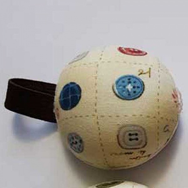 Bracelet porte-épingles rond avec motif de boutons de couture.