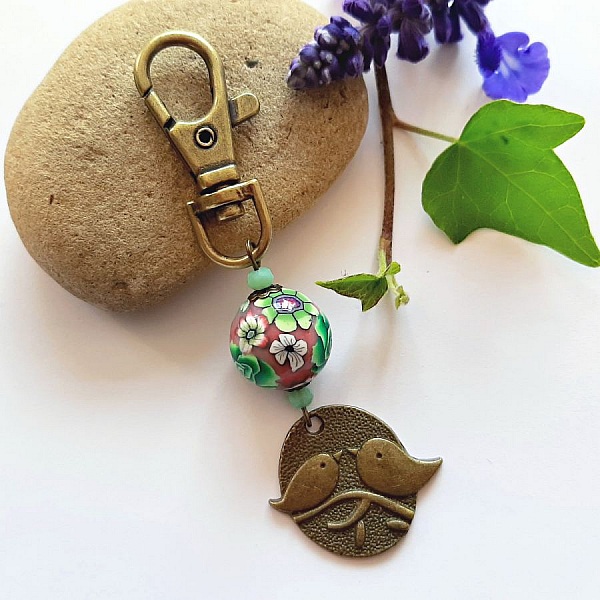 nyckelring medalj duo av f&aring;glar bronsf&auml;rg och p&auml;rla tillverkade blomm&ouml;nster gr&ouml;nt och vinbl&aring;ttmultikolour