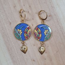 Orientalisk blomma hängande örhängen med blå bakgrund