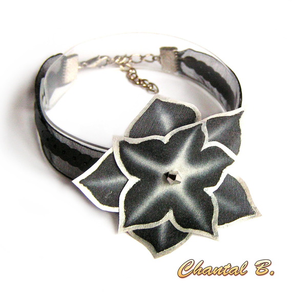 Svart bandarmband med paljetter och en handmålad svart och silverfärgad silkesblomma.