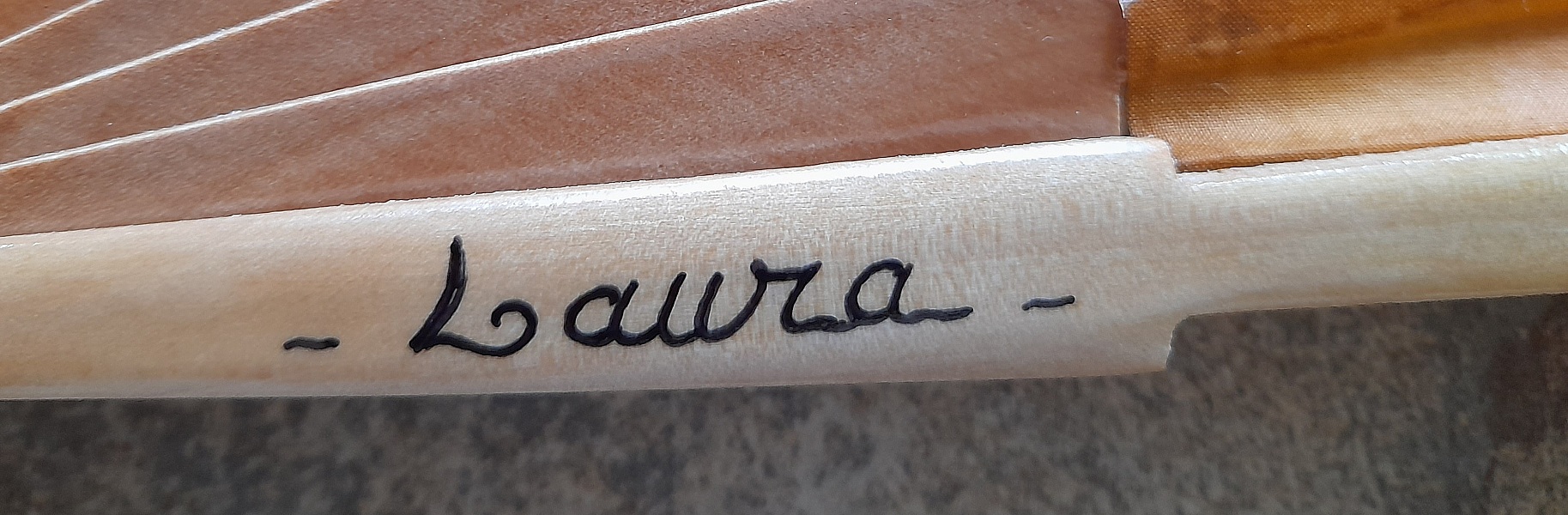 Signature de l'artiste sur un éventail artisanal en coton.