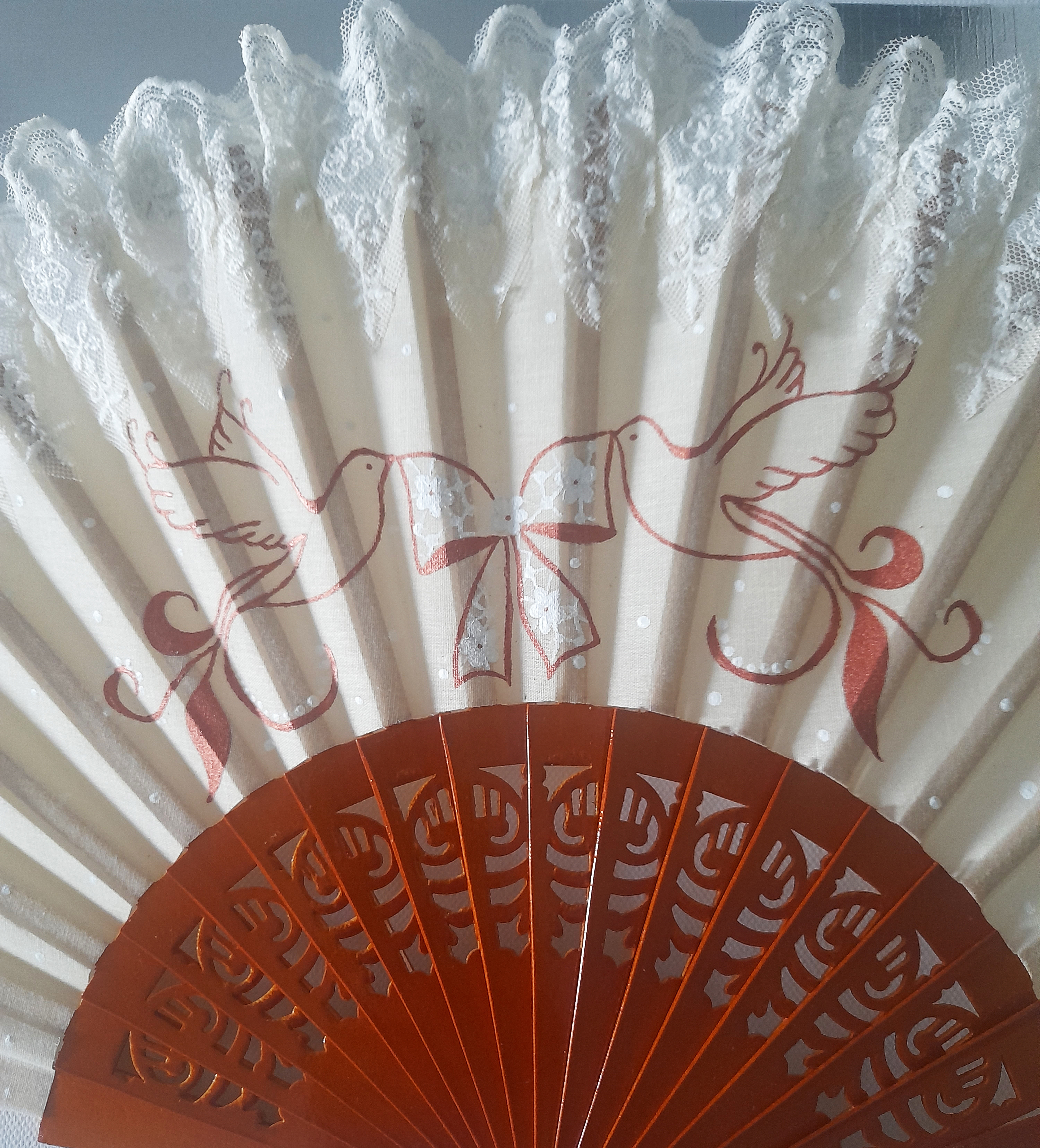 Éventail artisanal en dentelle avec motifs peints à la main.