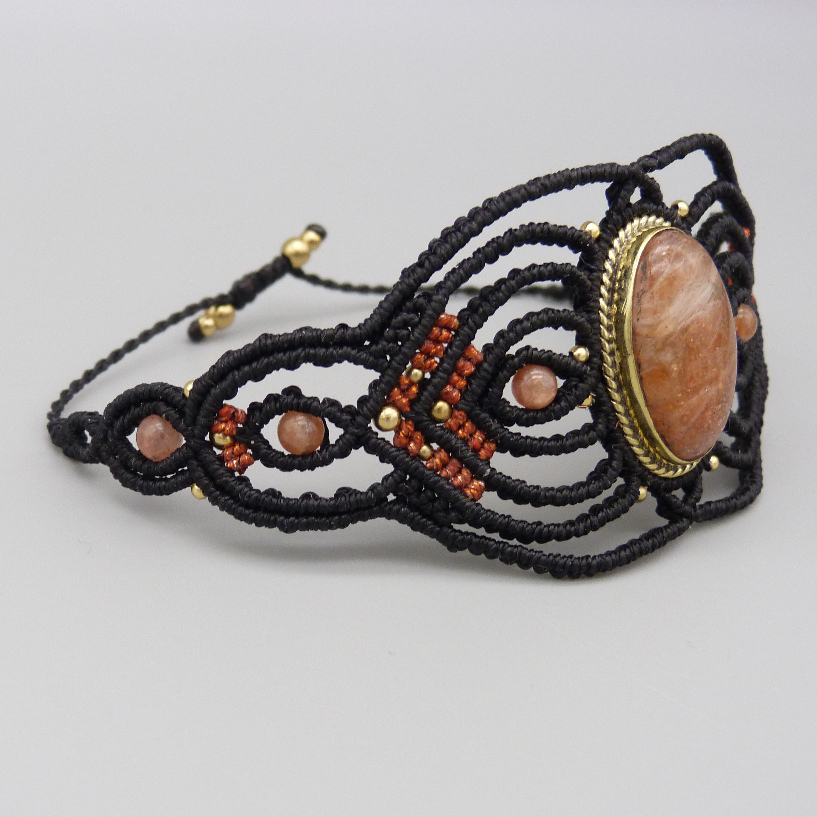 Manchette noire en micro-macramé avec une pierre de soleil