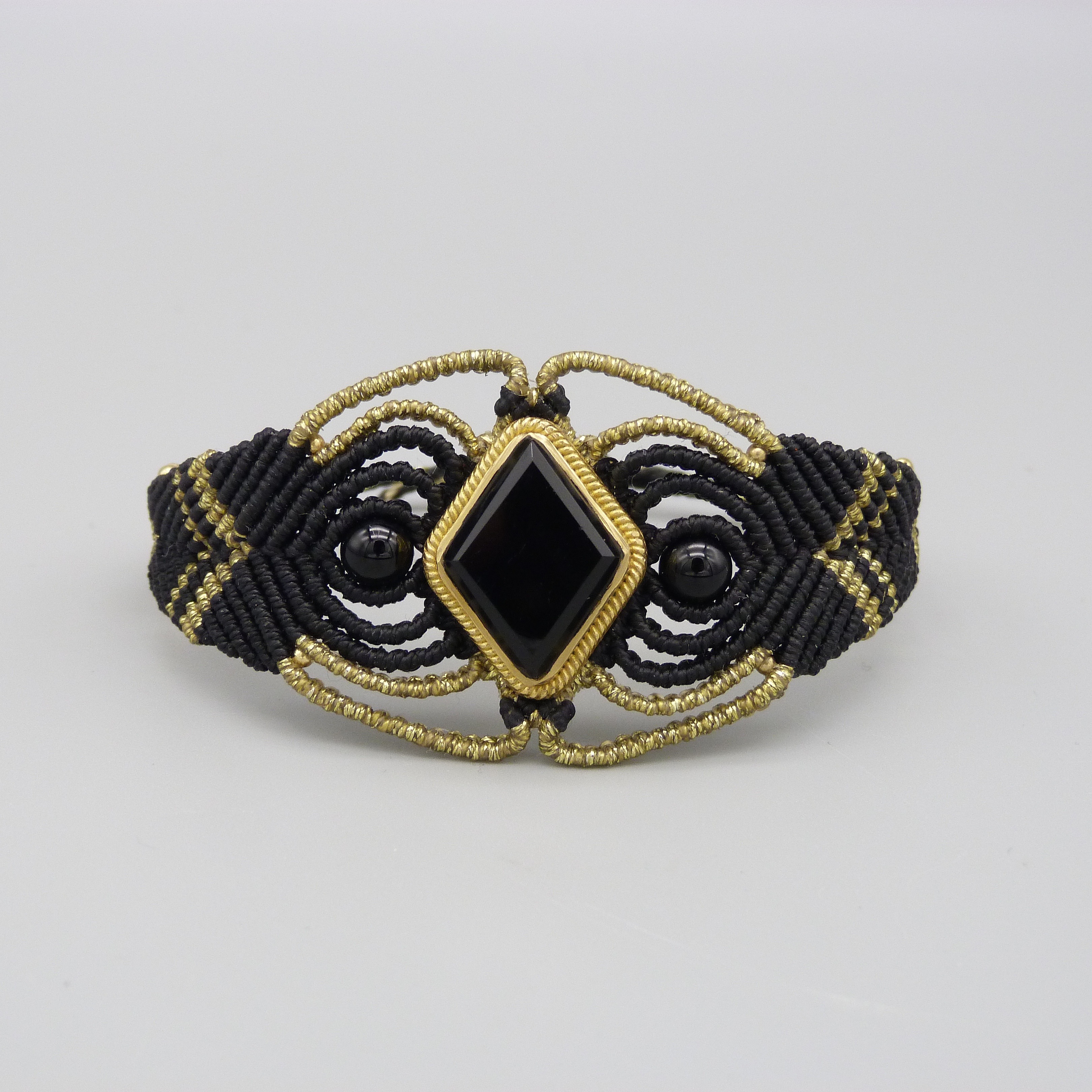 Manchette noire en micro-macram&eacute; avec une pierre onyx noire sertie de laiton