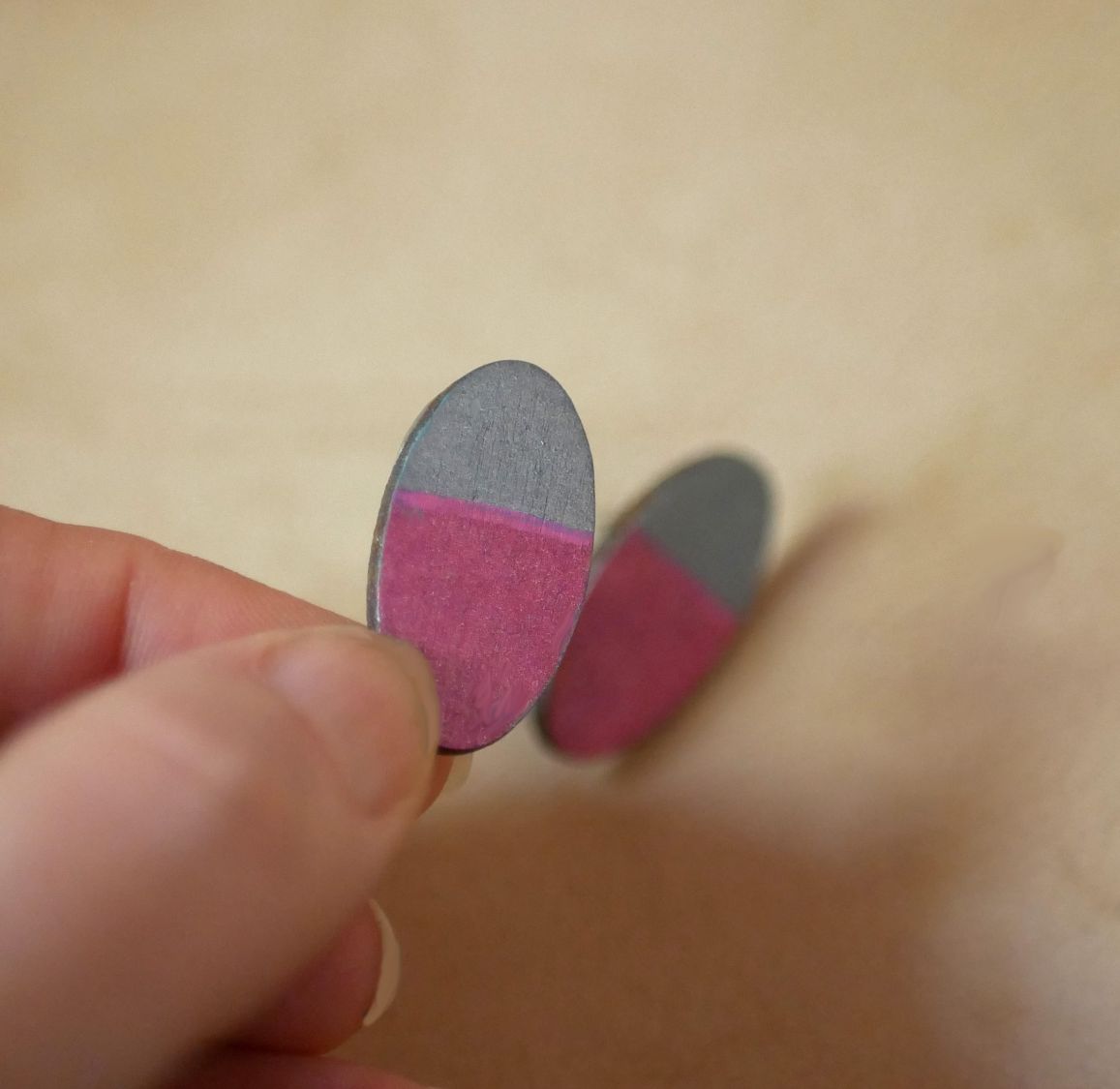 Ovala örhängen i trä målade i fuchsia och grå metallisk effekt.