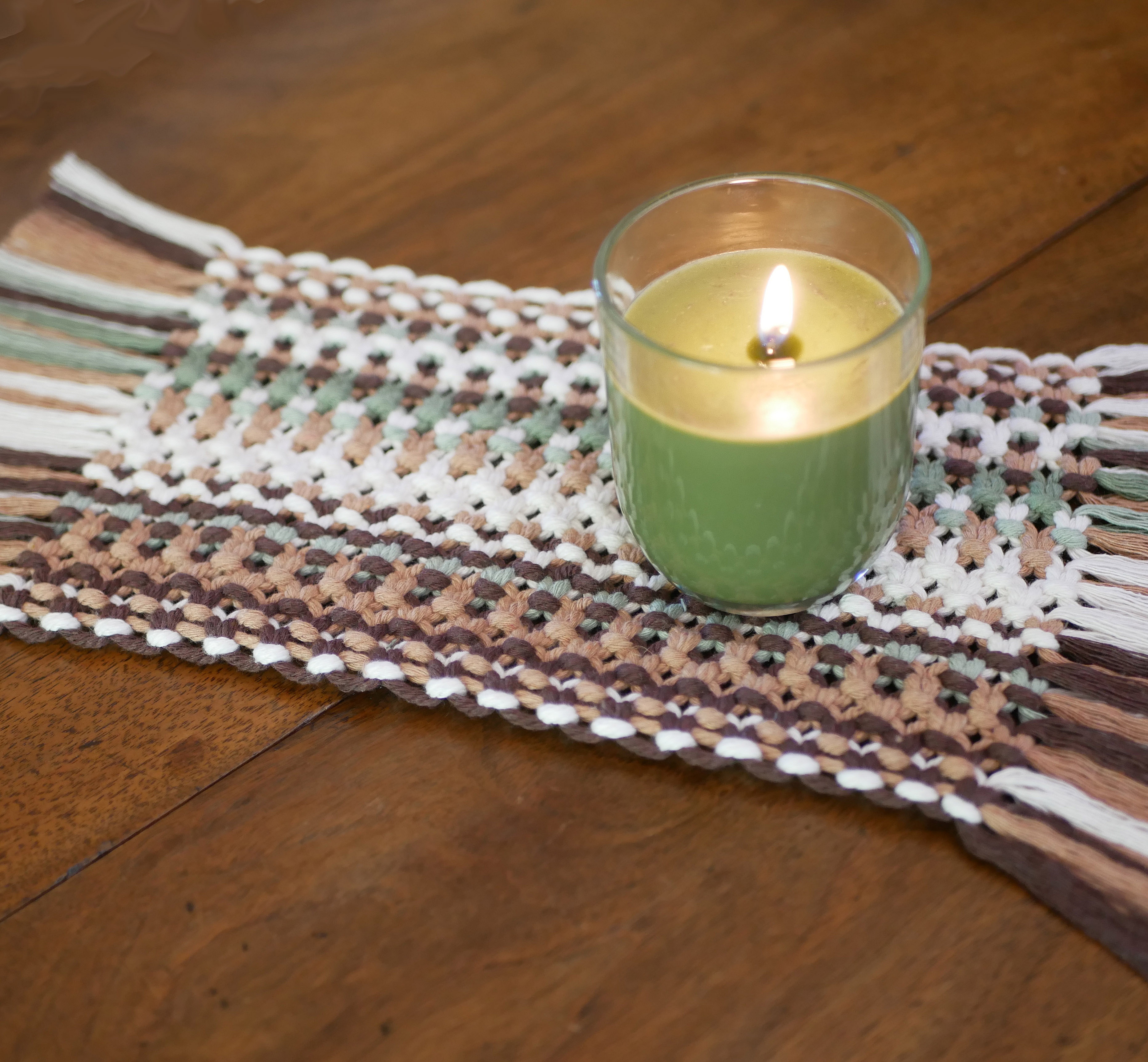 Set de table en macramé style forêt avec bougie allumée.