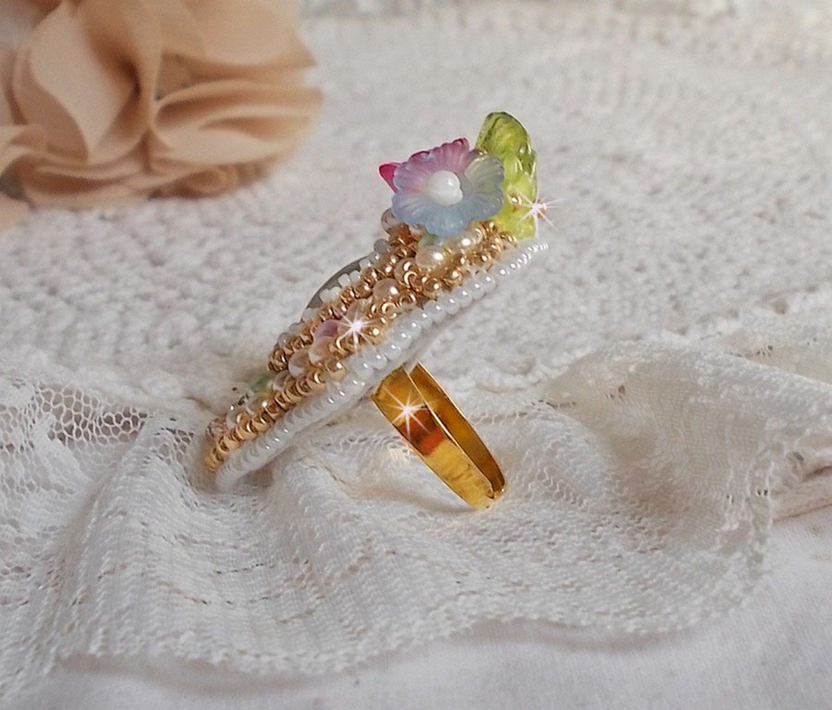 Envolée Fleurie ring broderad med en harts cabochon av Lucite blommor, pärlpärlor och fröpärlor.