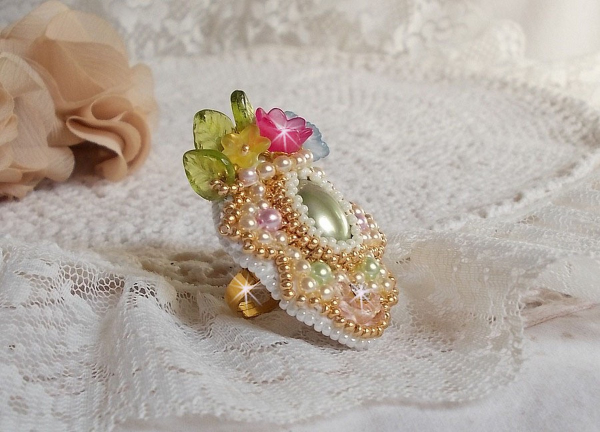 Envolée Fleurie ring broderad med en harts cabochon av Lucite blommor, pärlpärlor och fröpärlor.