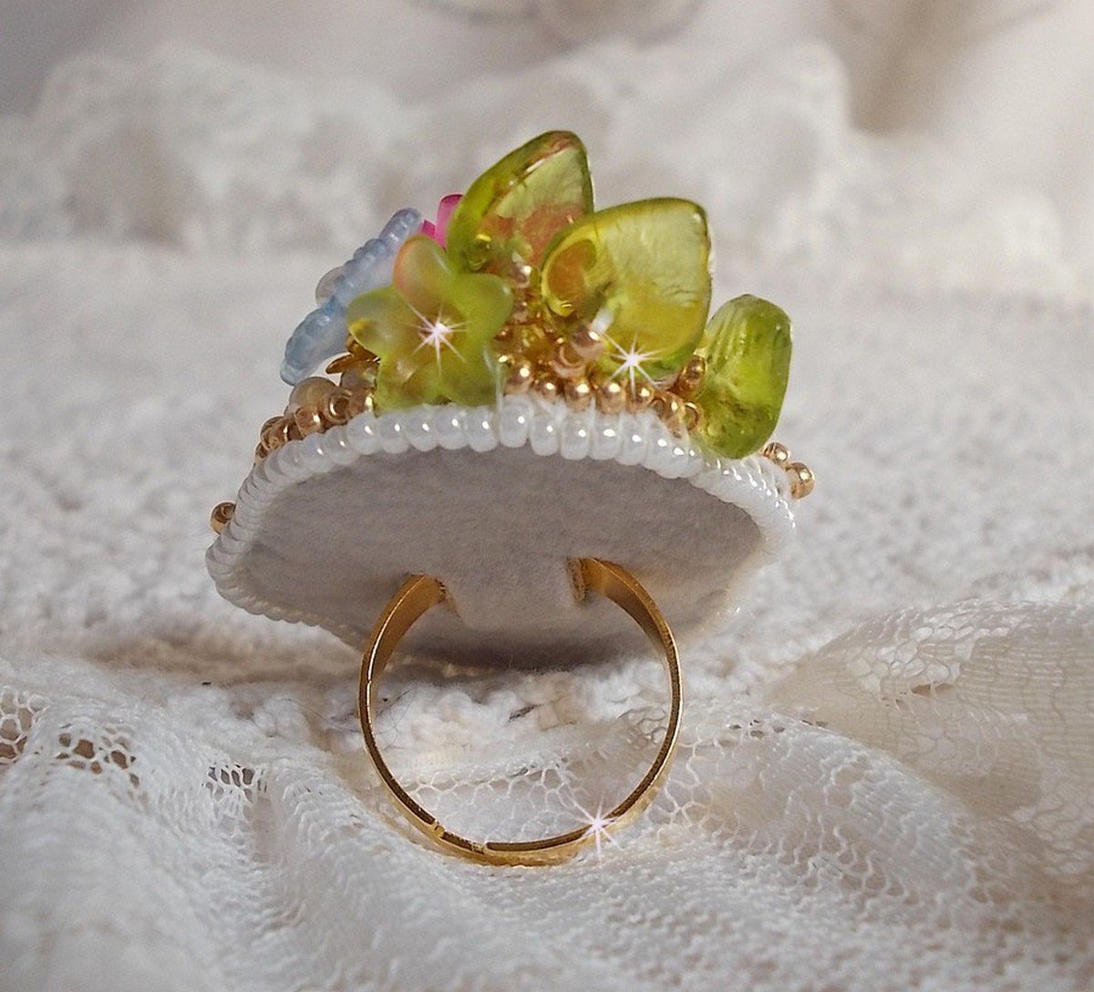 Envolée Fleurie ring broderad med en harts cabochon av Lucite blommor, pärlpärlor och fröpärlor.