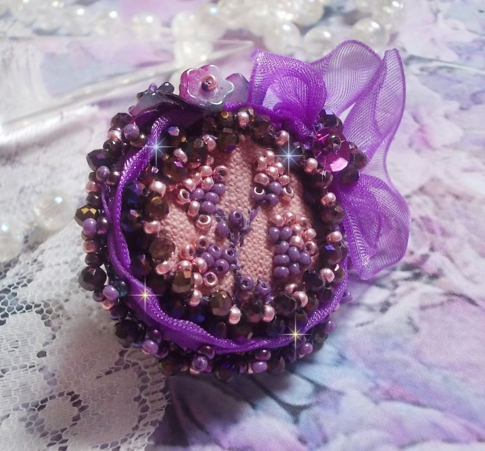 Romantisk Lady Ring broderad på ett rosa linnetyg med rosa, iris, lila och persika pärlor. 
