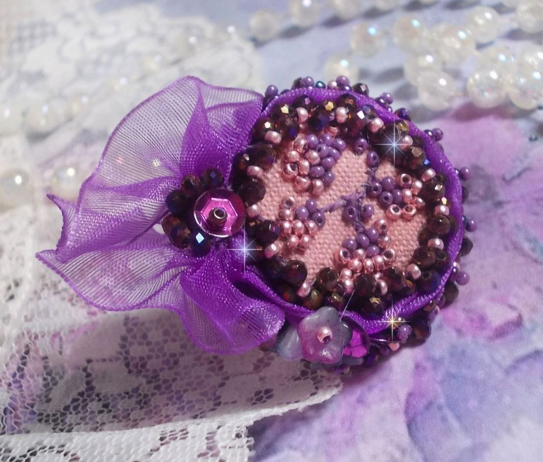 Romantisk Lady Ring broderad på ett rosa linnetyg med rosa, iris, lila och persika pärlor. 