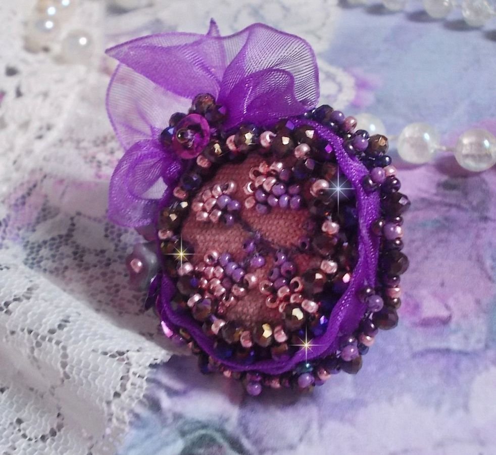 Romantisk Lady Ring broderad på ett rosa linnetyg med rosa, iris, lila och persika pärlor. 