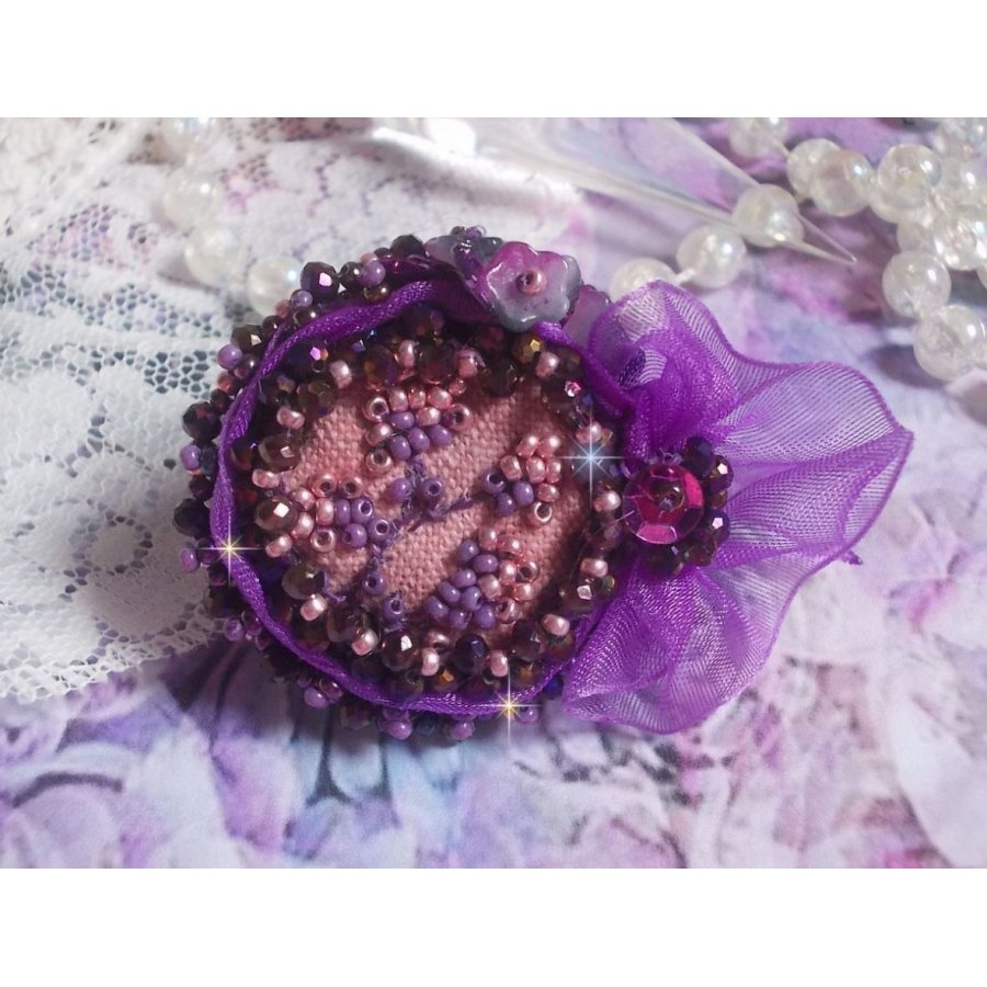 Romantisk Lady Ring broderad på ett rosa linnetyg med rosa, iris, lila och persika pärlor. 