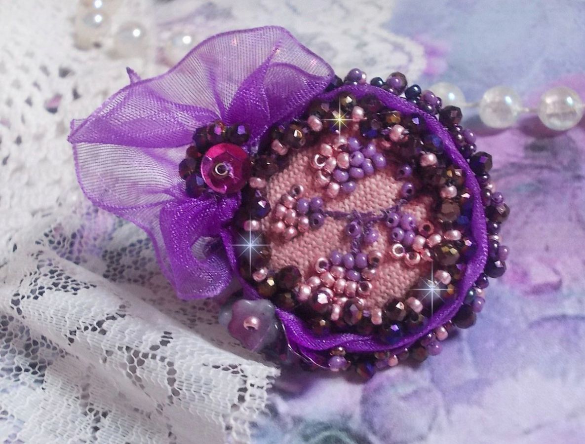 Romantisk Lady Ring broderad på ett rosa linnetyg med rosa, iris, lila och persika pärlor. 