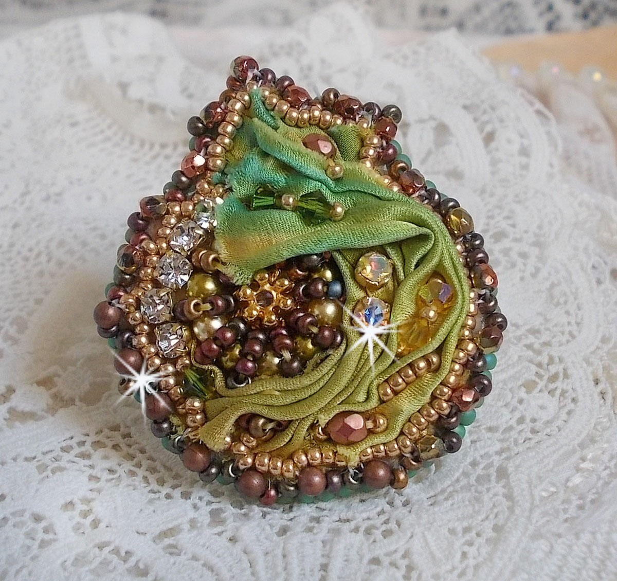 Venetiansk månring broderad med kameleonfärgat sidenband, Swarovskikristaller, olika pärlor och fröpärlor.