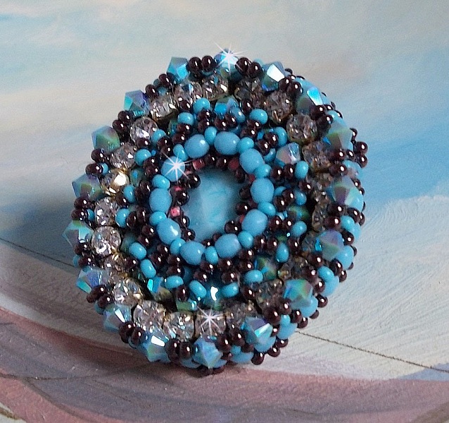 Na&iuml;ade ring broderad med en turkosbl&aring; harts och kristallcabochon, ett vackert ljusspel.