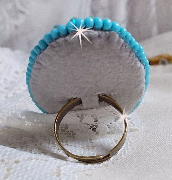 Turkos ring broderad med en turkos cabochon, PureCrystal spinnande toppar och fr&ouml;p&auml;rlor.