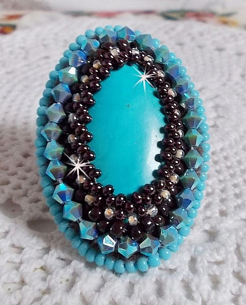 Turkos ring broderad med en turkos cabochon, PureCrystal spinnande toppar och fr&ouml;p&auml;rlor.