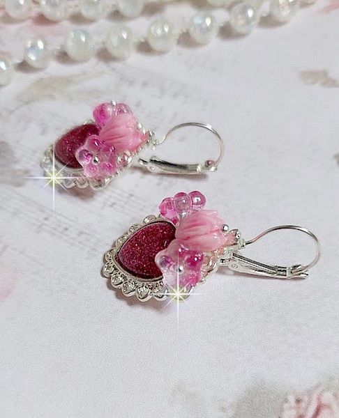 BO C&oelig;ur Ardent mont&eacute;es avec des dormeuses argent&eacute;es &agrave; laquelle s&rsquo;ajoute des c&oelig;urs paillet&eacute;s en r&eacute;sine Fuchsia. Ils sont orn&eacute;s d&rsquo;un bouquet de fleurs en verre &agrave; la couleur Rose pour un style romantique