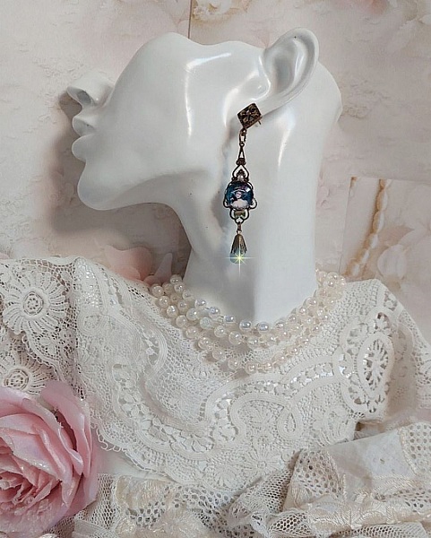 BO Dame au chapeau fleuri repr&eacute;sentant une femme au chapeau entour&eacute; d&rsquo;un ruban noir est mont&eacute; sur des estampes avec des n&oelig;uds en cristal. Une belle &eacute;l&eacute;gance avec ces gouttes en Jade teint&eacute;es de Bleu