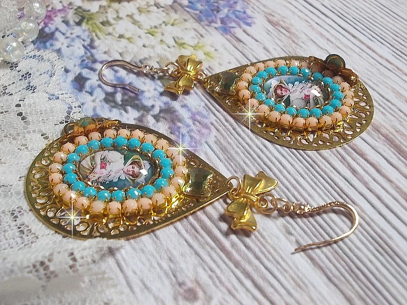 BO Mademoiselle Noellia avec des cabochons ovales repr&eacute;sentant une femme avec un chapeau et un n&oelig;ud blanc &agrave; laquelle s&rsquo;ajoute des cristaux, cha&icirc;nes strass P&ecirc;che et Turquoise sur crochets en plaqu&eacute; Or