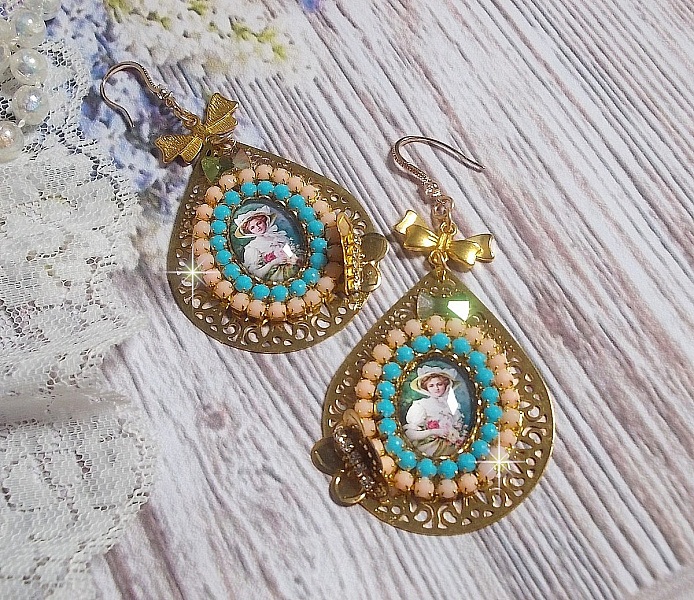 BO Mademoiselle Noellia avec des cabochons ovales repr&eacute;sentant une femme avec un chapeau et un n&oelig;ud blanc &agrave; laquelle s&rsquo;ajoute des cristaux, cha&icirc;nes strass P&ecirc;che et Turquoise sur crochets en plaqu&eacute; Or