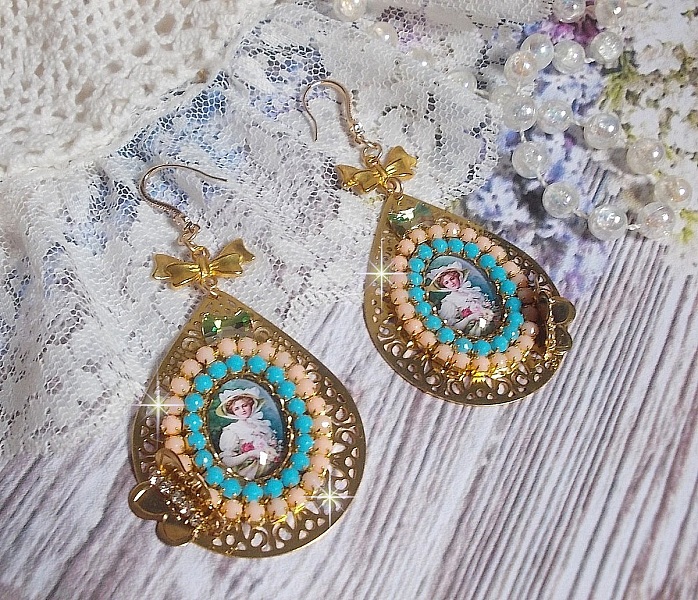 BO Mademoiselle Noellia avec des cabochons ovales repr&eacute;sentant une femme avec un chapeau et un n&oelig;ud blanc &agrave; laquelle s&rsquo;ajoute des cristaux, cha&icirc;nes strass P&ecirc;che et Turquoise sur crochets en plaqu&eacute; Or