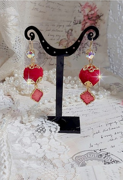 BO Passionn&eacute;ment mont&eacute;es avec des pompons Rouges tr&egrave;s tendances &agrave; laquelle s&rsquo;ajoute des coupelles en forme d&rsquo;arabesque, pendentifs vitrail Rouge/Dor&eacute; et cabochons en Cristal AB sur crochets en Laiton