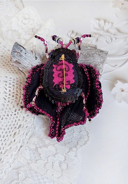 Dos de broche insecte brodée rose fuchsia et noir.