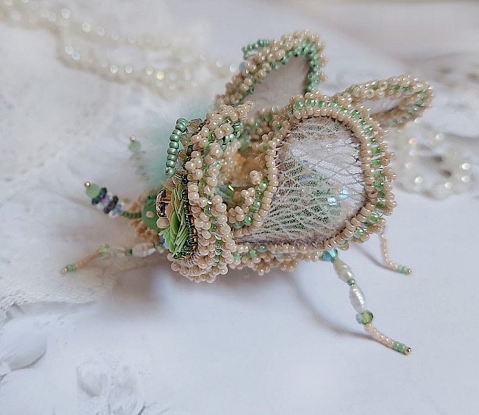 Broche artisanale en forme d'insecte brodée de perles délicates.