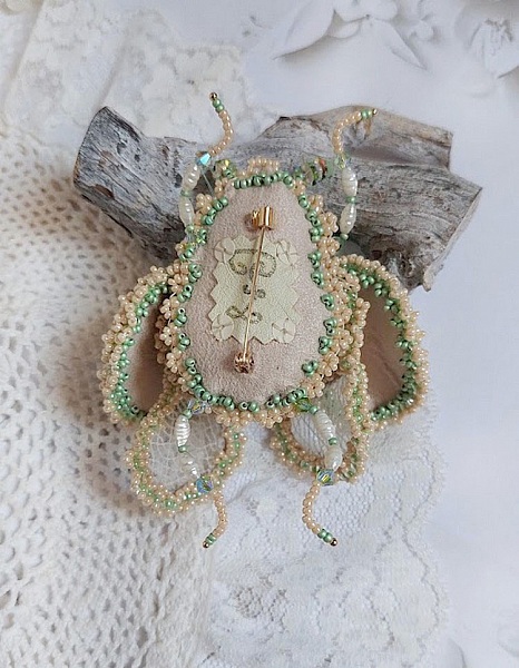 Dos d'une broche Mouchon artisanale brodée de perles délicates.