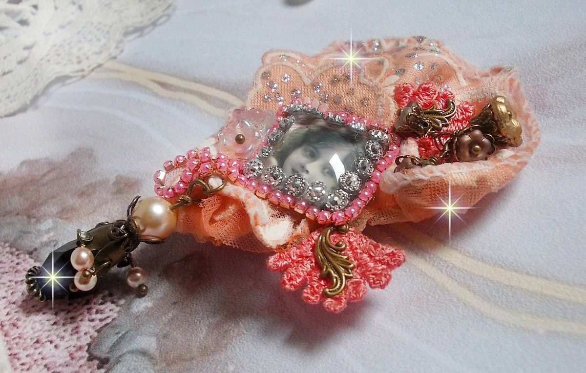 Rustik Rose brosch skapad med en cabochon som föreställer en leende flicka, orange strass och Rose spets, kristaller, glaspärlor och olika tillbehör.