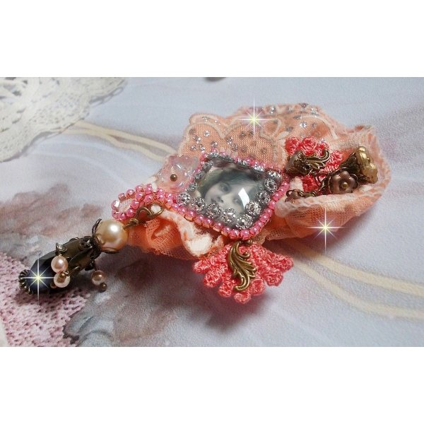 Rustik Rose brosch skapad med en cabochon som föreställer en leende flicka, orange strass och Rose spets, kristaller, glaspärlor och olika tillbehör.