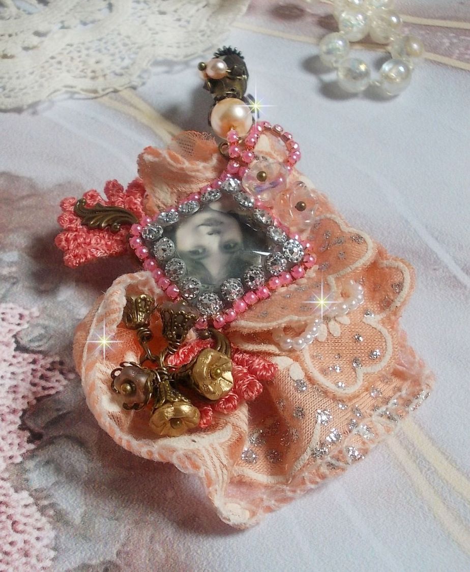 Rustik Rose brosch skapad med en cabochon som föreställer en leende flicka, orange strass och Rose spets, kristaller, glaspärlor och olika tillbehör.