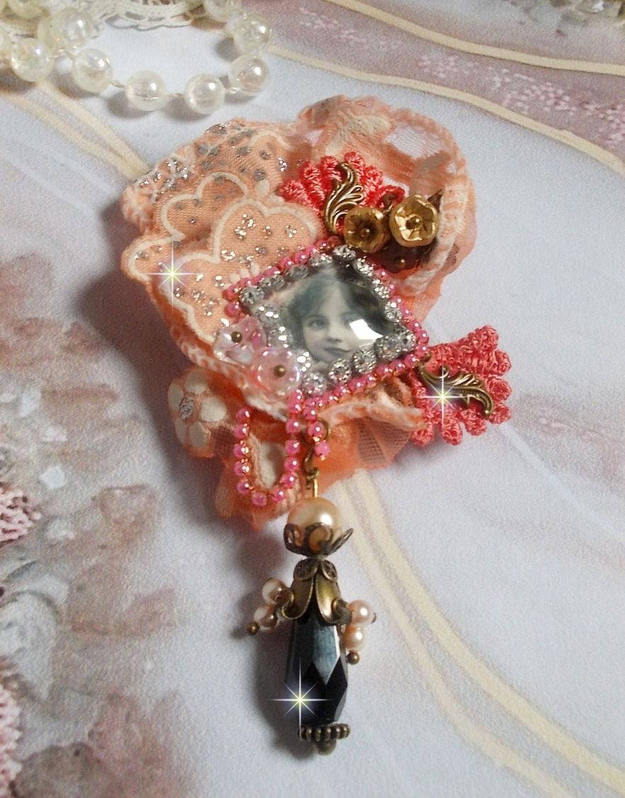 Rustik Rose brosch skapad med en cabochon som föreställer en leende flicka, orange strass och Rose spets, kristaller, glaspärlor och olika tillbehör.
