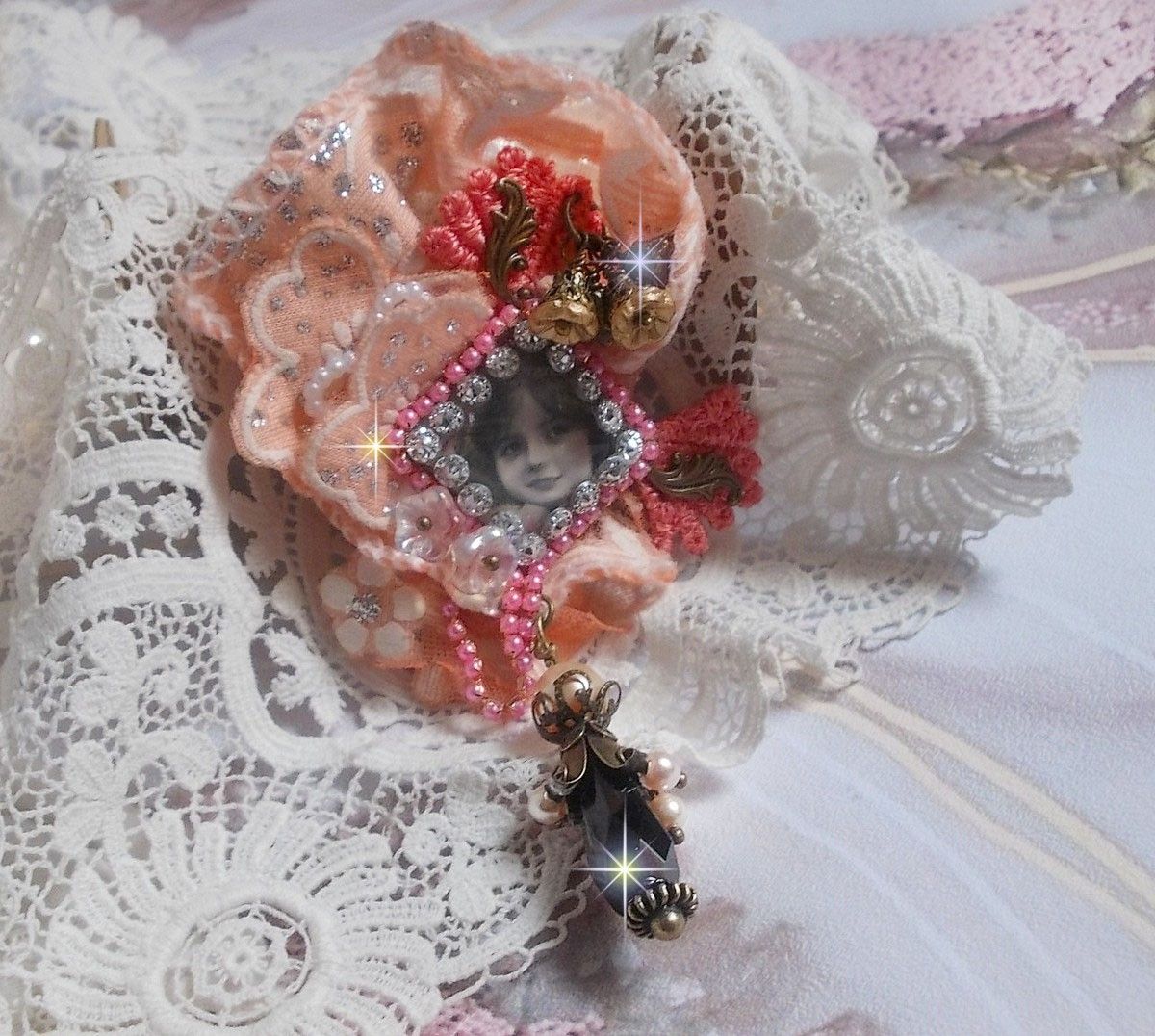 Rustik Rose brosch skapad med en cabochon som föreställer en leende flicka, orange strass och Rose spets, kristaller, glaspärlor och olika tillbehör.