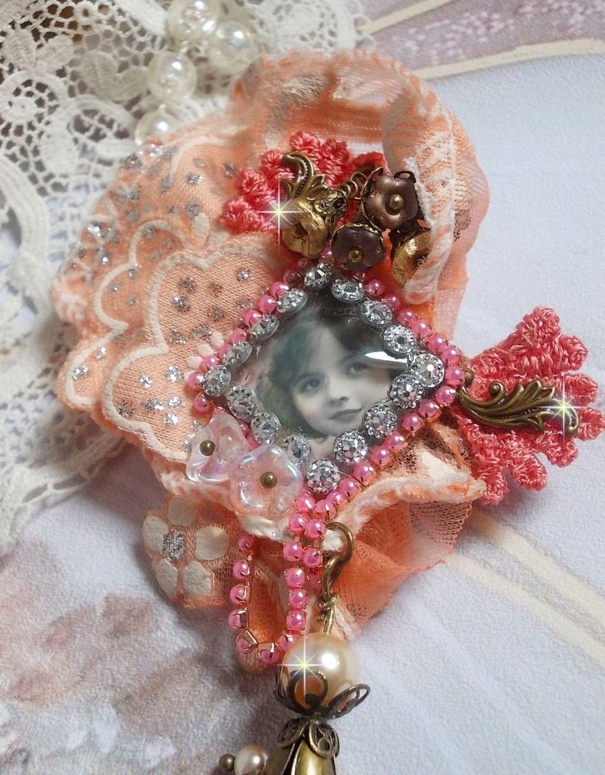 Rustik Rose brosch skapad med en cabochon som föreställer en leende flicka, orange strass och Rose spets, kristaller, glaspärlor och olika tillbehör.