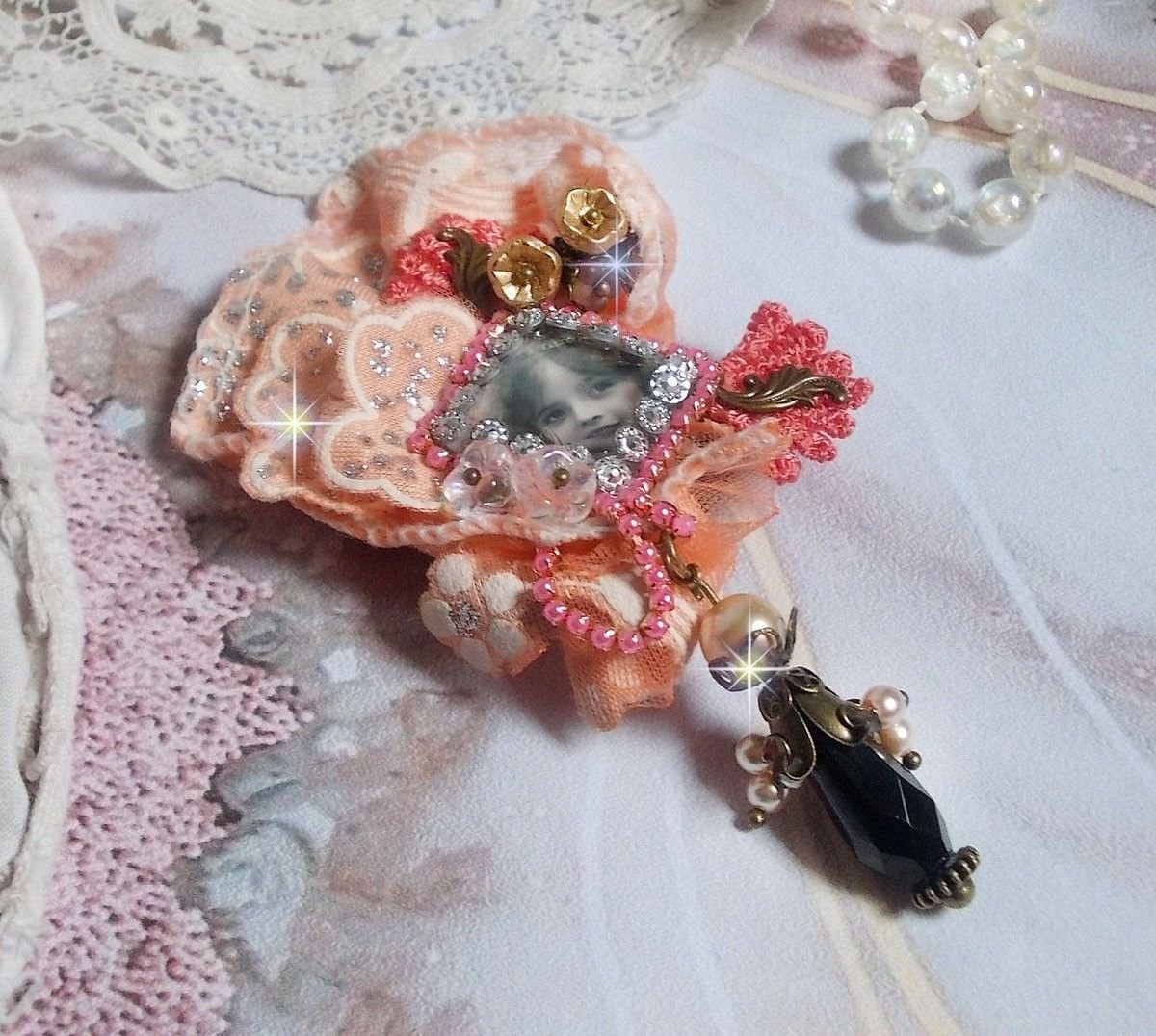 Rustik Rose brosch skapad med en cabochon som föreställer en leende flicka, orange strass och Rose spets, kristaller, glaspärlor och olika tillbehör.