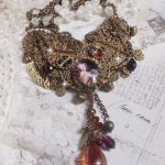 Mes Passions Brocs halsband skapar en kvinna med gyllene hår med blommor, bronsaccessoarer, kristallberlocker och en strass-kedja.