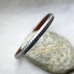 Kvinnoarmband i mörkgrått metalliskt läder med silverfärgade pärlor 