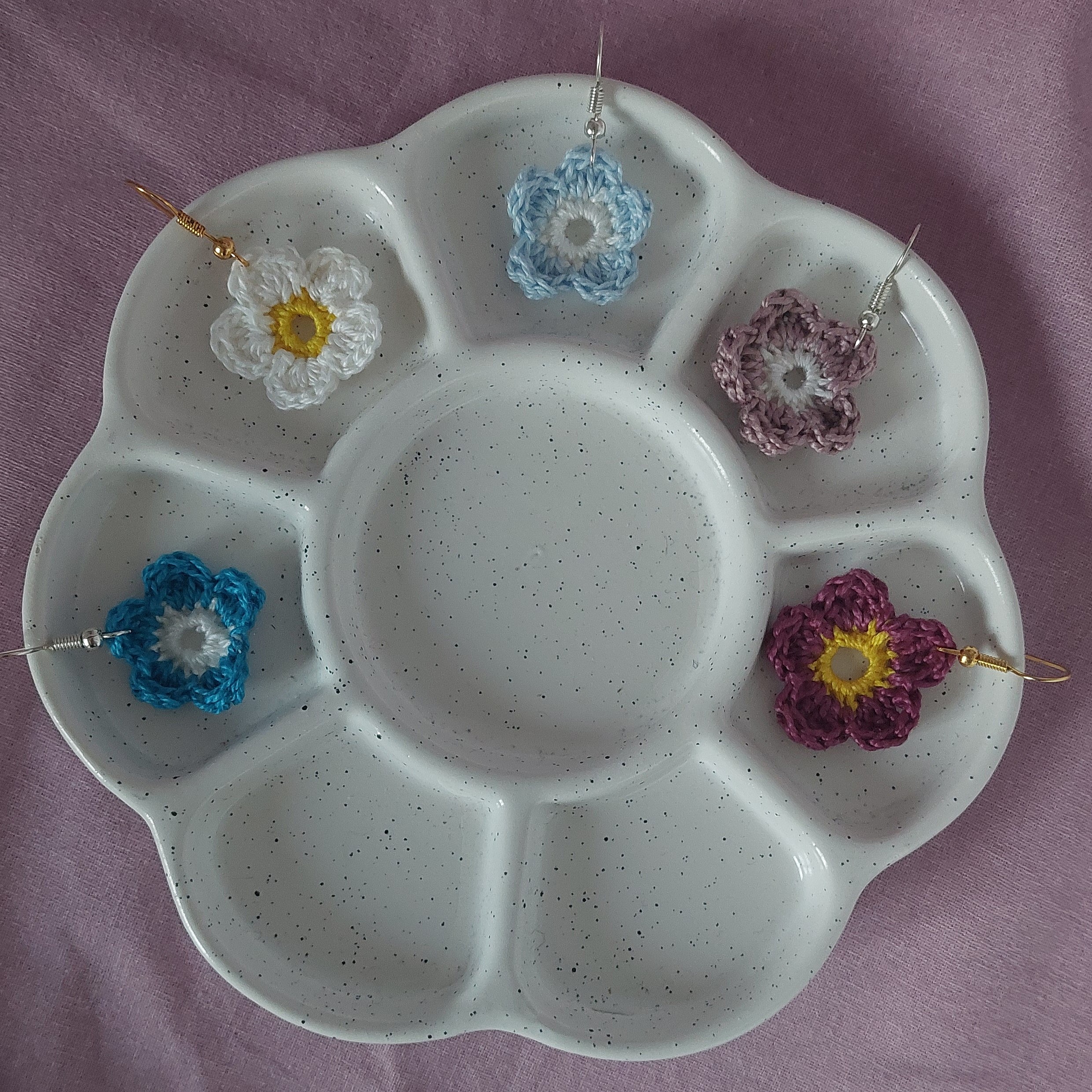Boucles d'oreilles fleurs au crochet colorées sur palette blanche.